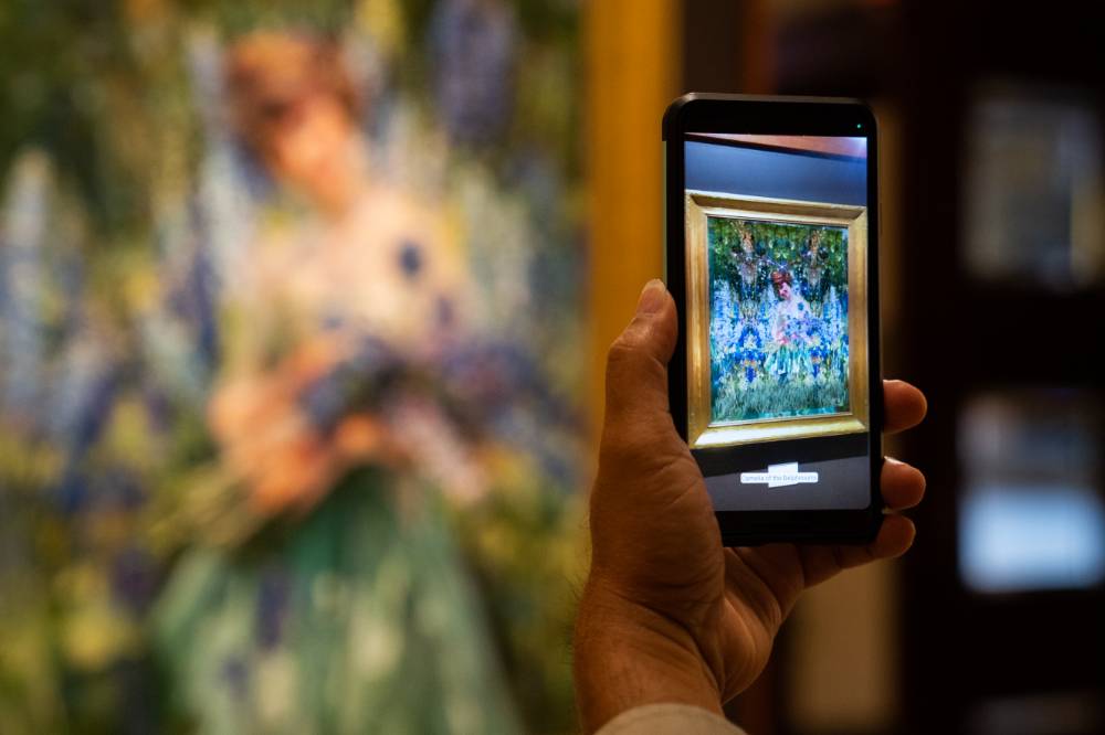 Guest taking photos of the art on a smart phone